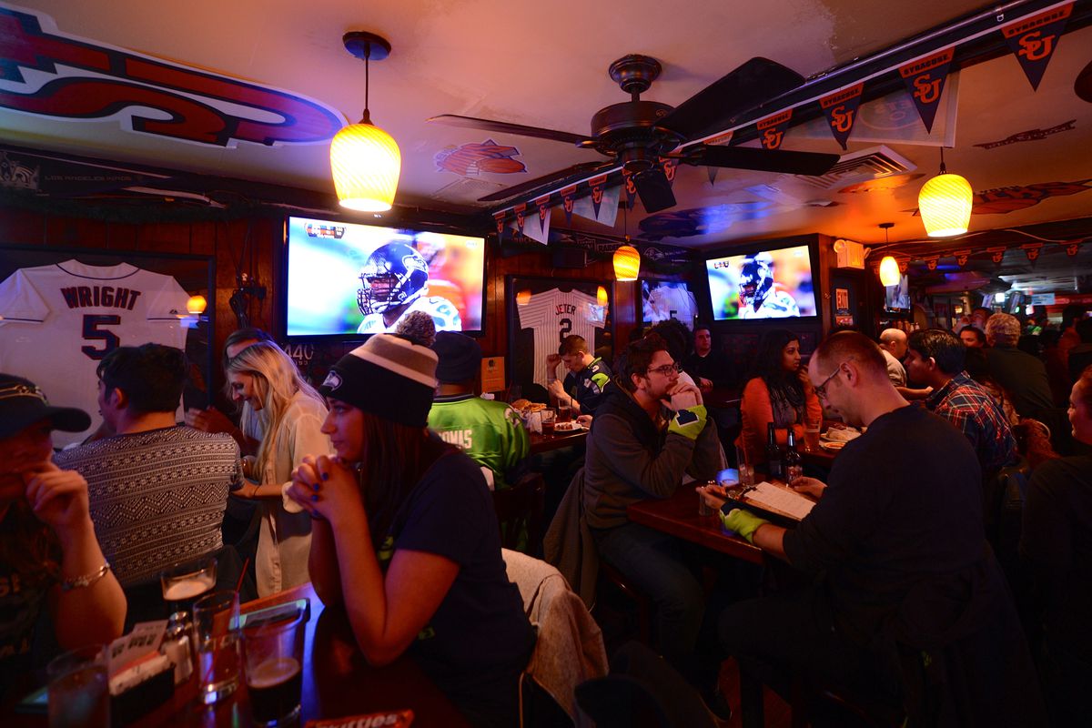 Football fans watch the NFL Super Bowl XLVIII game between the Denver Broncos and the Seattle Seahawks on television at a sports bar in New Jersey, USA, on February 2, 2014.