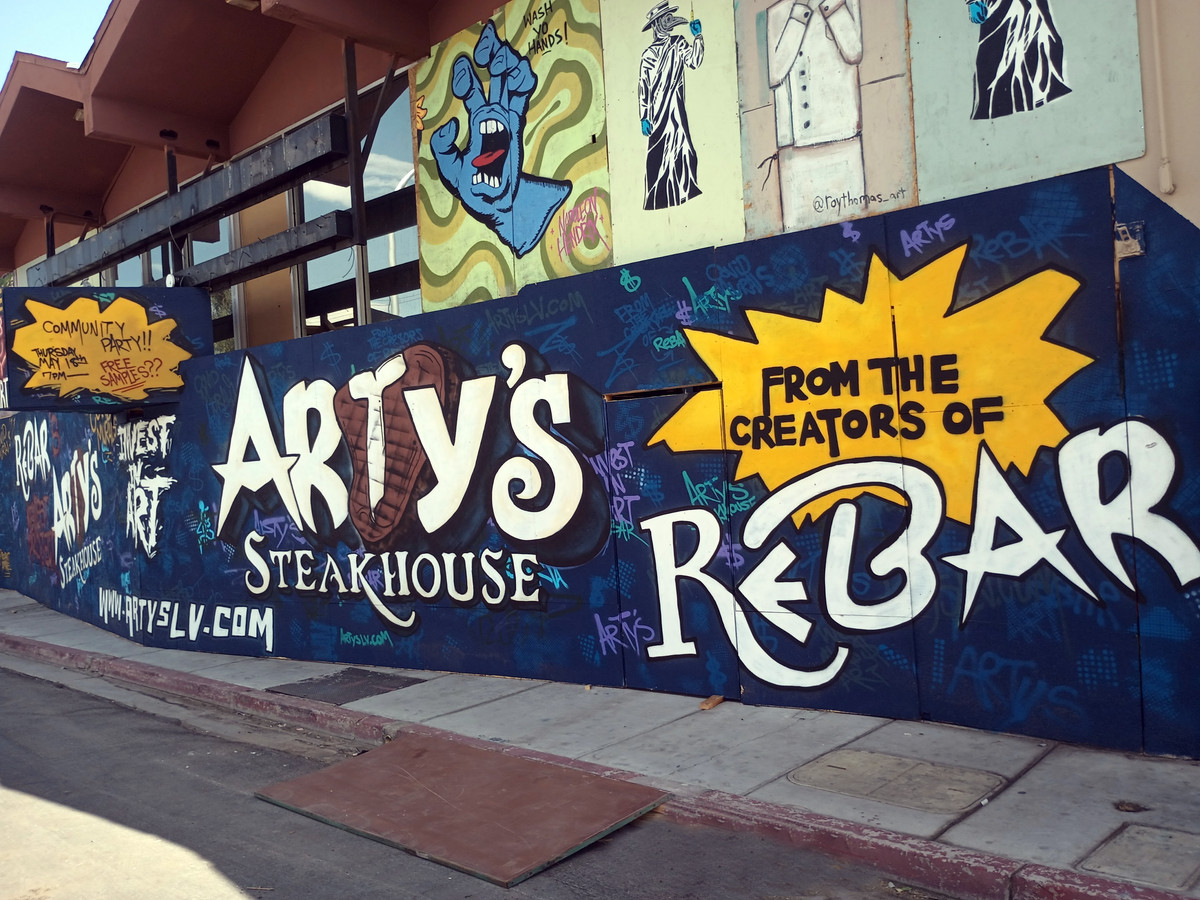 Temporary wall in front of building with hand-painted words that say “Arty’s Steakhouse from the creators of Rebar.”