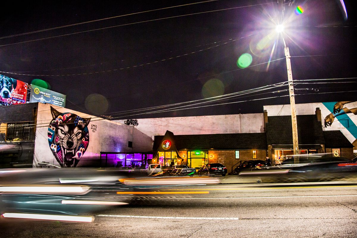 A nighttime shot of restaurant and bar 8ARM located on Ponce de Leon Avenue in Atlanta with cars rushing by