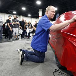 An employee demonstrates how to wrap a car in front of an audience at the AutoRama car show at the South Towne Expo Center in Sandy on Friday, March 4, 2016.