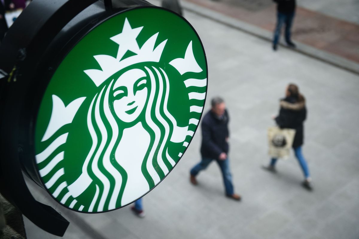 A Starbucks sign looks down on two pedestrians