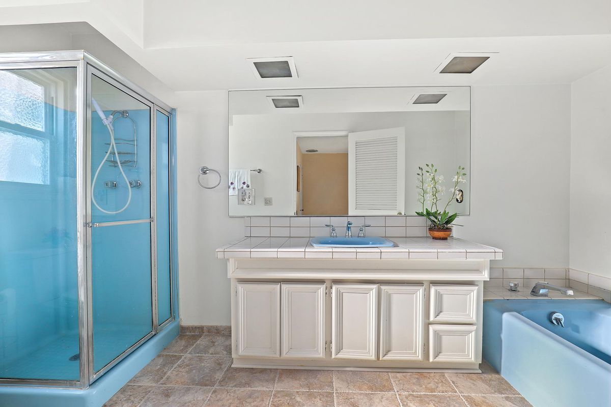 A bathroom with a blue shower enclosure and seaparate blue bathtub.