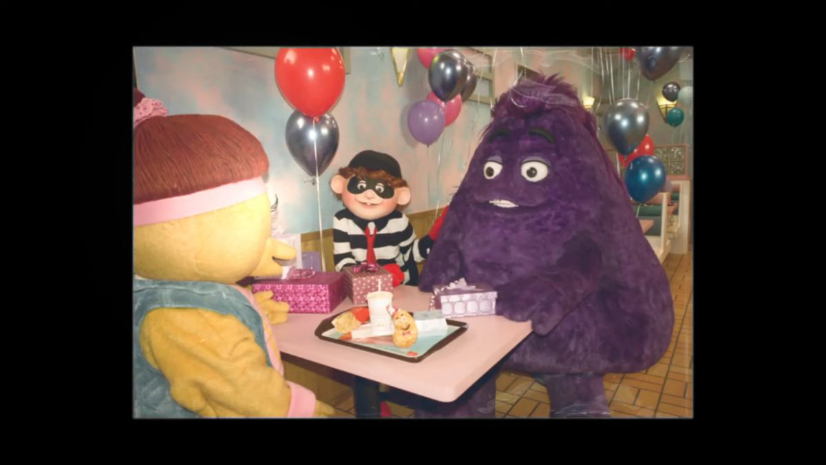 An old photo of Grimace, the Hamburgler, and a Birdie and Early Bird sitting around a table, eating McDonald’s.