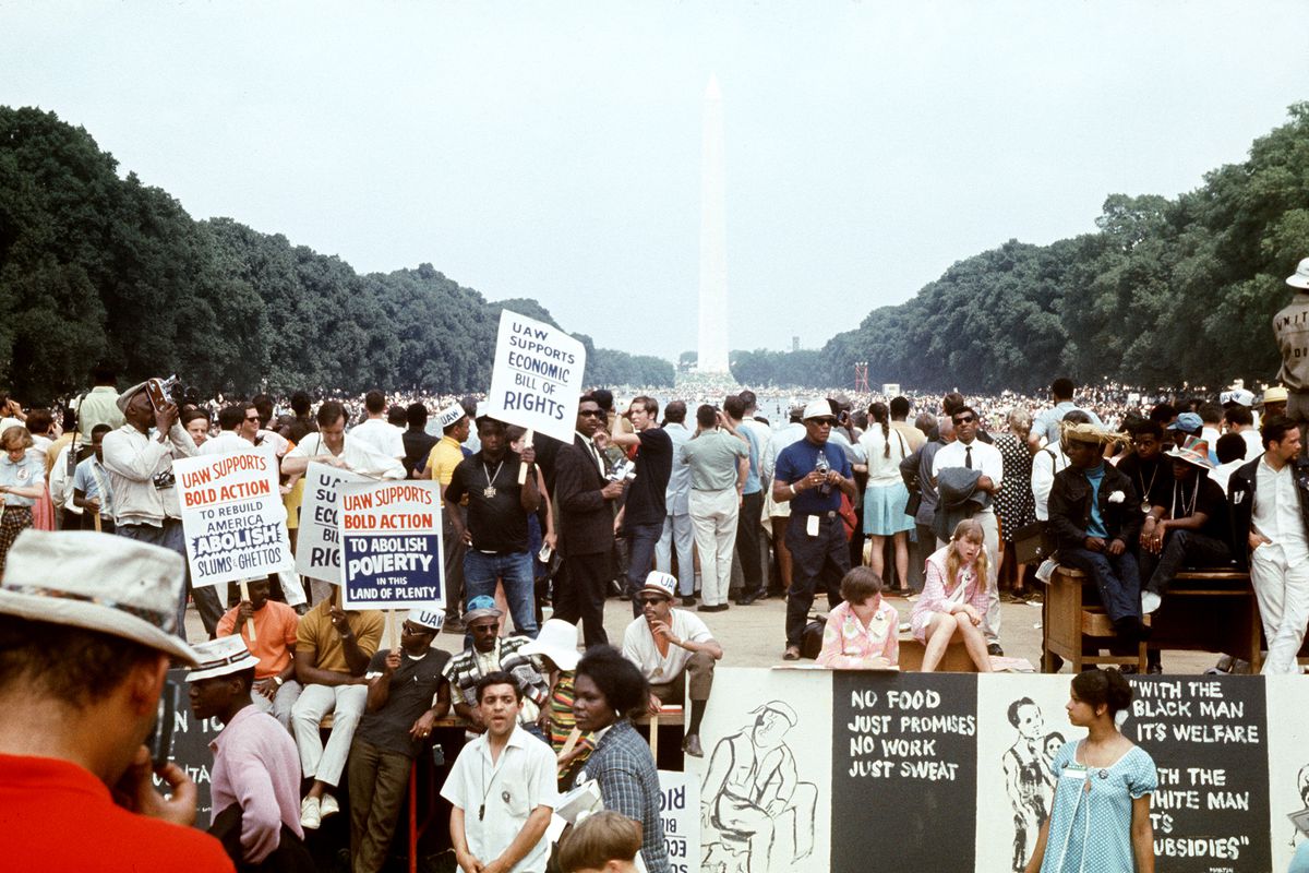 Protesters with signs gather on the Washington, DC, mall with the Washington Memorial obelisk in the background.