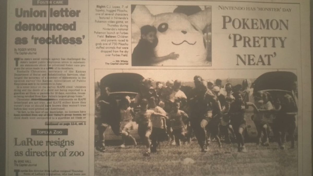 Una edición antigua del Topeka Capital Journal, con coloración en tonos sepia.  Una pequeña imagen muestra a un niño abrazando un peluche gigante de Pikachu.  El titular del lector 