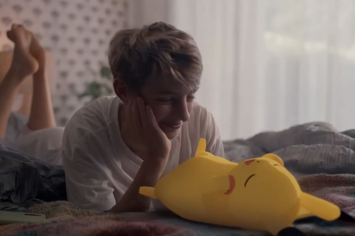 A woman looks at a sleeping Pikachu in her bed