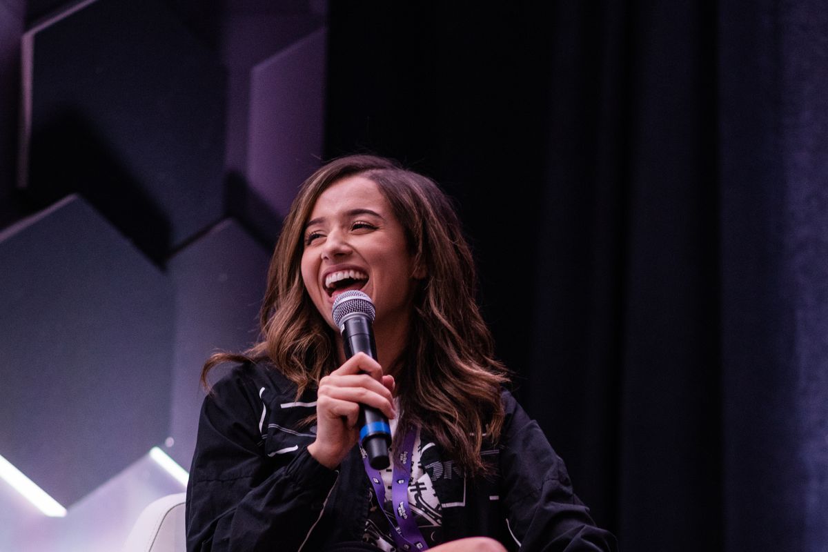 Twitch streamers Pokimane sitting on a stage holding a microphone 