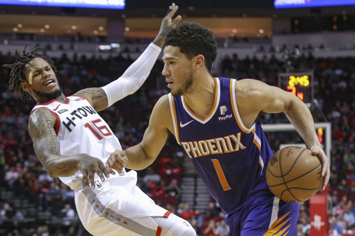 Phoenix Suns guard Devin Booker is called for a charge against Houston Rockets guard Ben McLemore in the first quarter at Toyota Center.