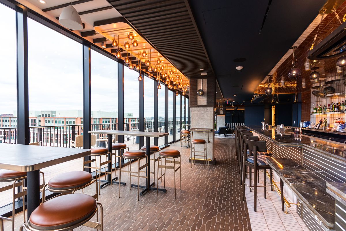 Wall-to-wall windows offer a view from a heated indoor space at the rooftop bar