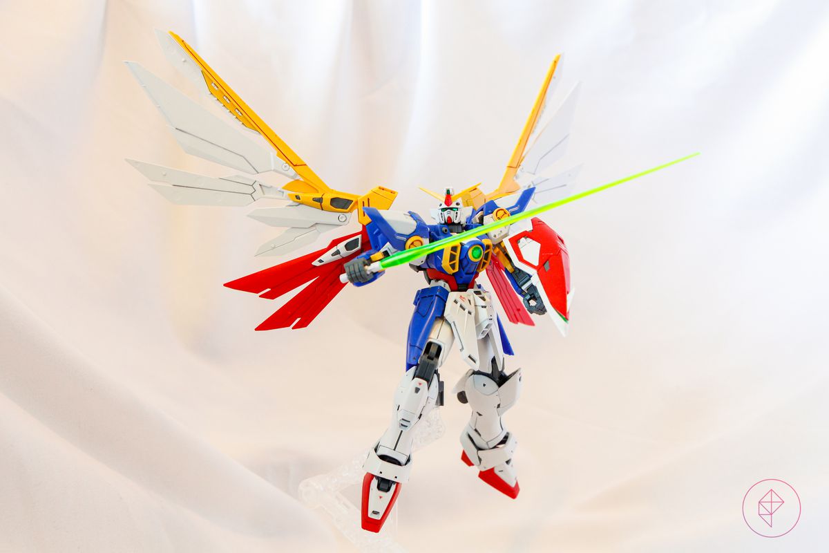 The Wing Gundam Gunpla kit floats in the air, supported by a clear plastic stand.