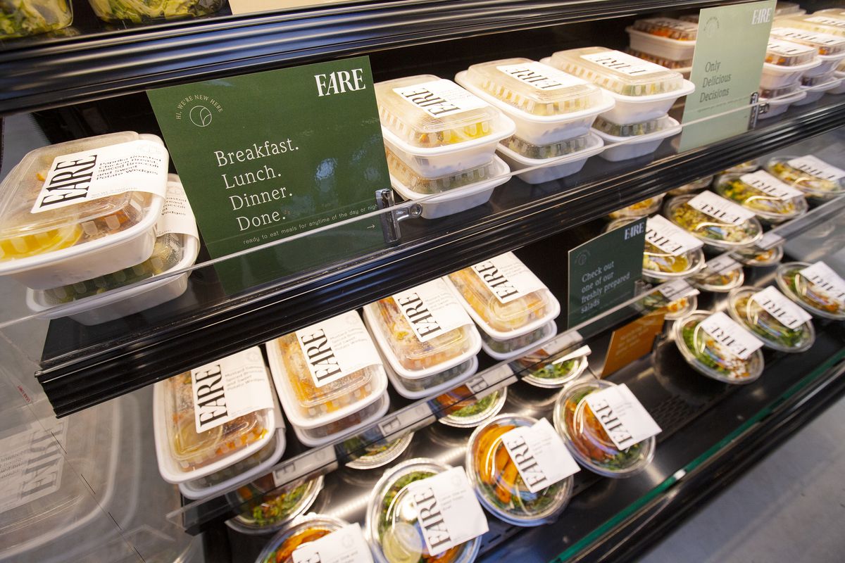 A series of shelves that hold prepared meals in to-go boxes.