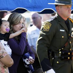 Christy Ivie, wife of U.S. Border Patrol agent Nicholas J. Ivie, wipes a tear during  a graveside ceremony for agent Ivie in Spanish Fork, Thursday, Oct. 11, 2012. At left, her 22-month-old daughter, Presley, points to helicopters flying over.