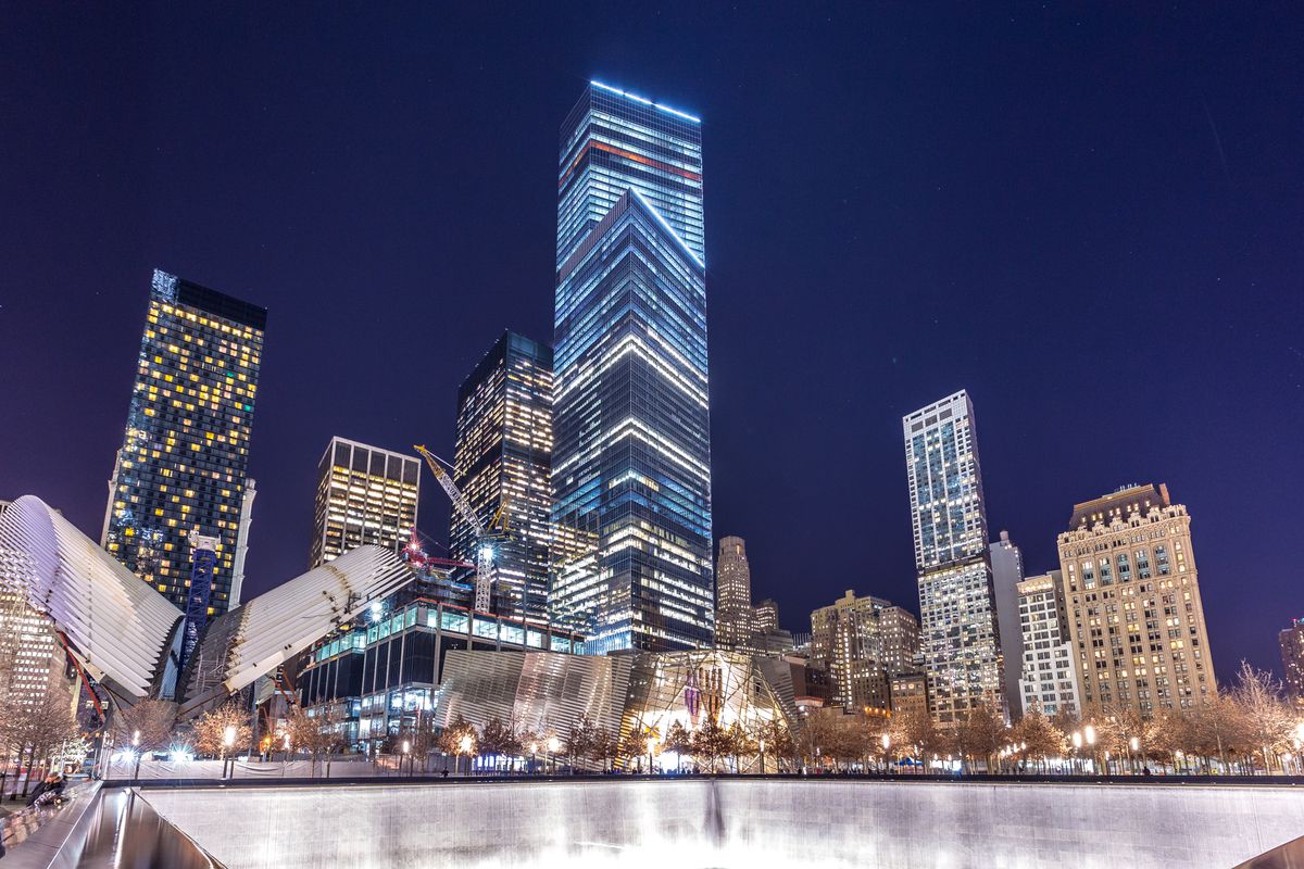 The skyscrapers and buildings at the World Trade Center site. In the foreground is a large memorial fountain.