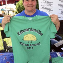 In a June 10, 2017 photo, Edwardsville Pierogi Festival Commitee member Carolyn Bren holds up one of the T-shirts for sale during the 2017 Edwardsville Pierogi Festival in Edwardsville, Pa. The Pennsylvania celebration of the popular Polish treat is embroiled in a food fight after the Whiting Pierogi Fest in Indiana threatened a trademark infringement lawsuit over the use of the name "Pierogi Festival."