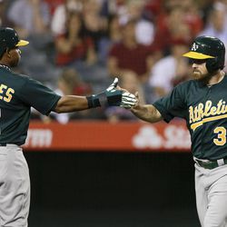 Oakland Athletics' Derek Norris, right, celebrates with Yoenis Cespedes after both scored on a single by Brandon Moss during the first inning of a baseball game against the Los Angeles Angels in Anaheim, Calif. Tuesday, April 9, 2013. 