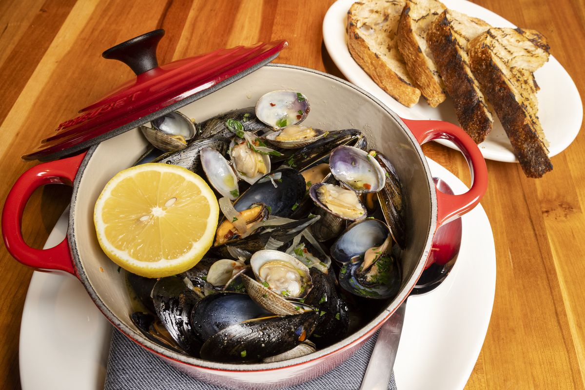 A big red pot holds a lemon and steamed mussels.