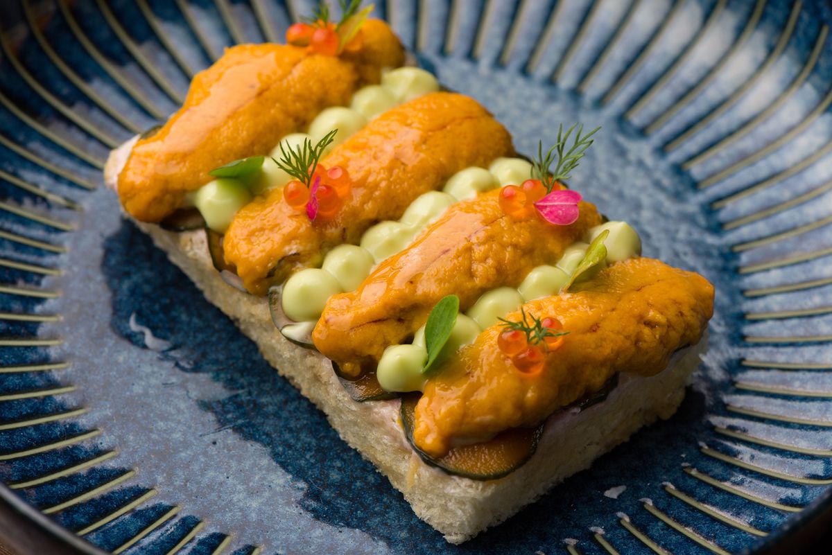 Uni toast with smoked trout roe at Tokki on a textured dark blue plate.