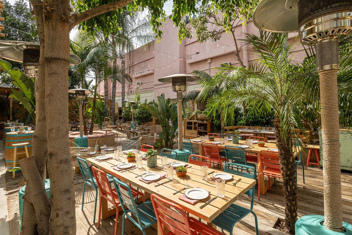 A long table set for service with colorful patio chairs at a new restaurant.