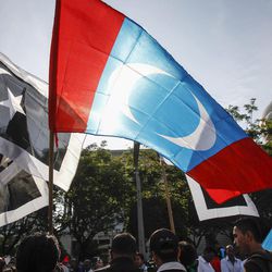 Supporters of Malaysian opposition leader Anwar Ibrahim waves People's Justice Party flag, center, in front of the Palace of Justice at Putrajaya, Malaysia, Tuesday, Feb. 10, 2015. Malaysia's top court has rejected a final appeal from Anwar and sent him back to jail in a case seen at home and aboard as politically motivated to eliminate any threats to the government. 