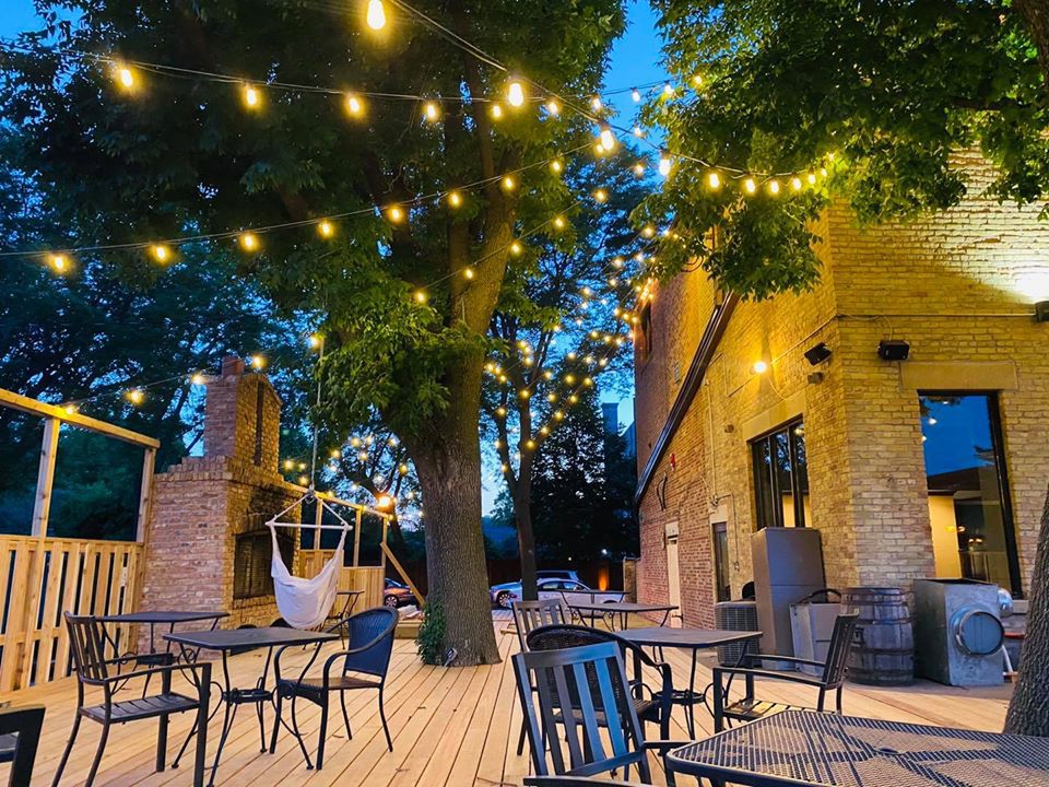 A patio at dusk, topped with bistro lights, under a tree