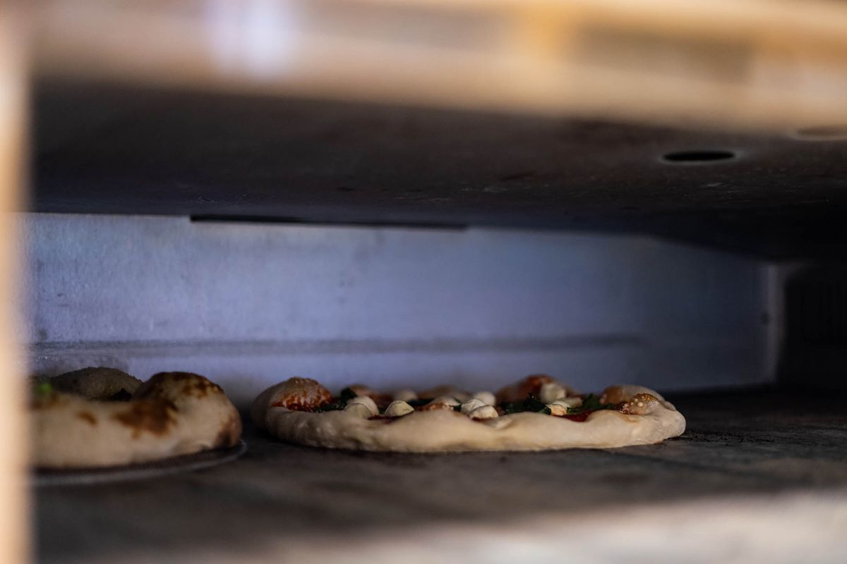 A deck oven pizza puffs up the cornicone of two pizzas at a restaurant.