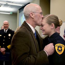 Steve Drott kisses his daughter, officer Josie Drott, after pinning on her badge during a Salt Lake City Police Department Academy graduation ceremony at the Pioneer Precinct in Salt Lake City on Friday, March 4, 2016. Drott was thankful for feeling well enough to watch his daughter graduate after recently having a stem cell transplant to fight his cancer. Fifteen Salt Lake police and two fire department recruits spent 23 weeks training in the police academy. Beginning Monday, the new officers will embark on 15 weeks of field training with veteran officers in order to be certified for solo patrol work. 