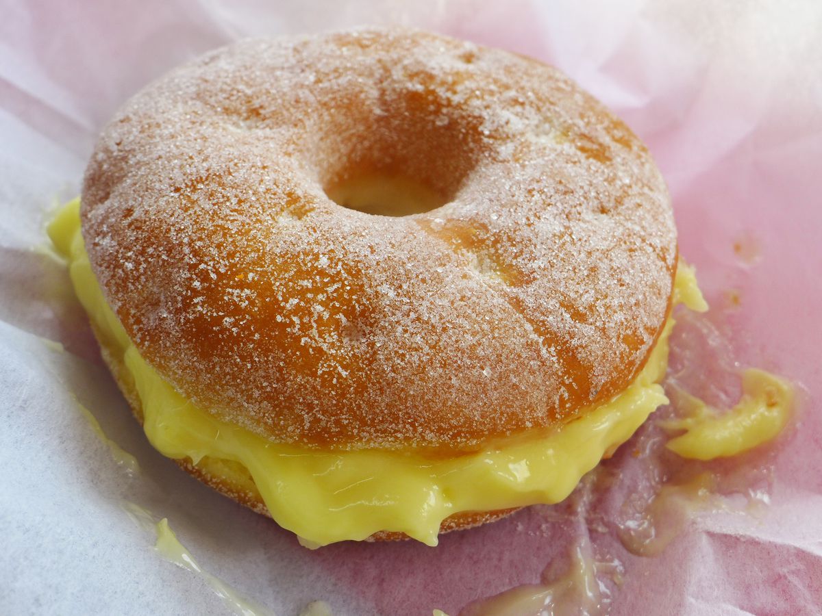 Donut split horizontally with yellow custard inside.