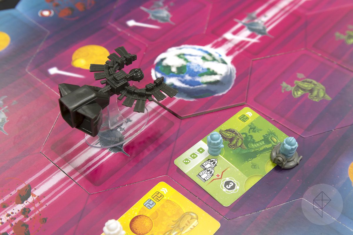 A miniature representing the Black Angel colony ship sails on towards the cardboard tile representing the Earth-like world of Spes. A planet in the foreground has been visited by tiny robots, agents of one of the game’s four competing AI.