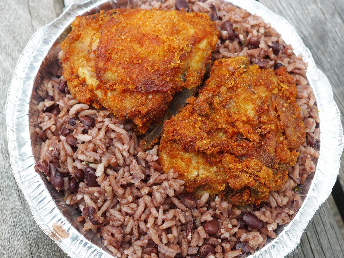 Two pieces of chicken on a bed of dark rice with the occasional black bean visible.