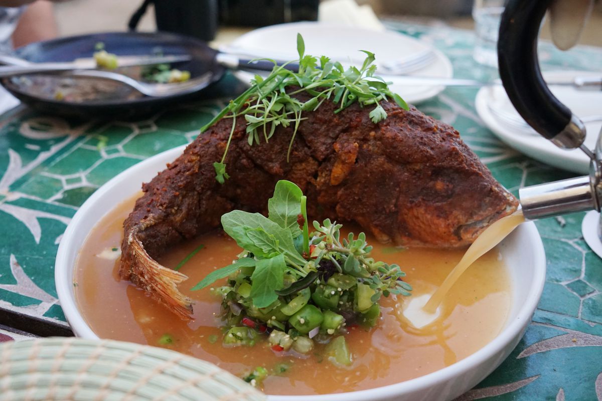Whole fried snapper in a pool of jus.