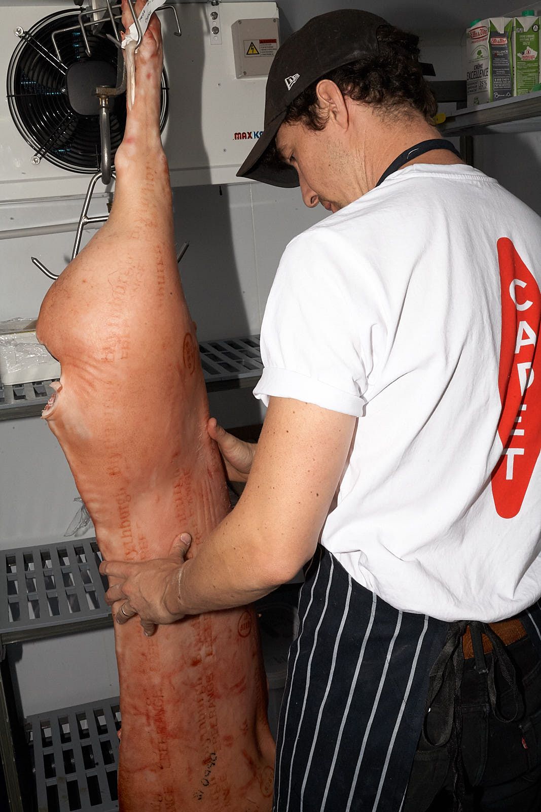A man cradles a pig carcass.