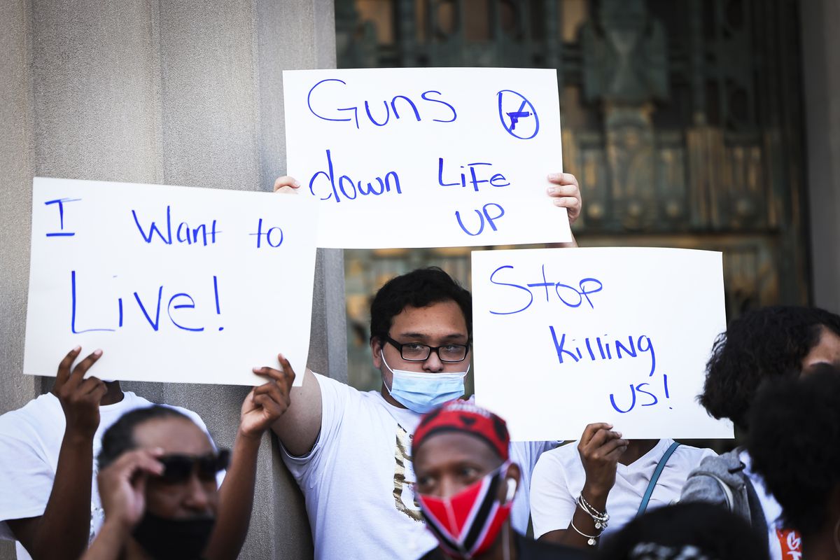 People hold up signs such as “Stop killing us!” at a rally.