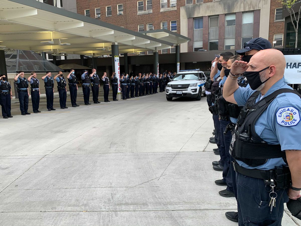 Members of the police department salute the two wounded officers after they were discharged from Mt. Sinai, May 16, 2021. Tom Schuba/Sun-Times 
