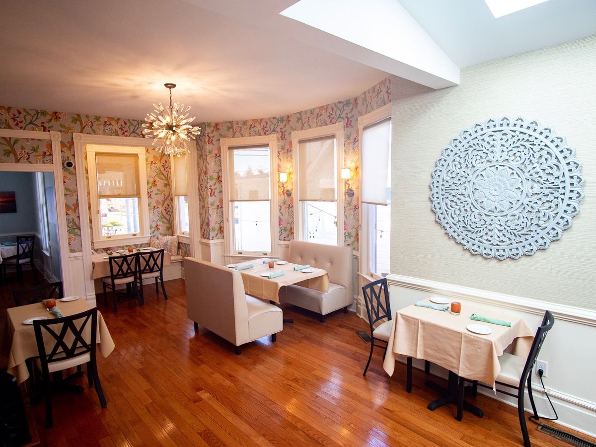 The dining room at Raas with wood flooring, tables topped with white linens, and natural light.