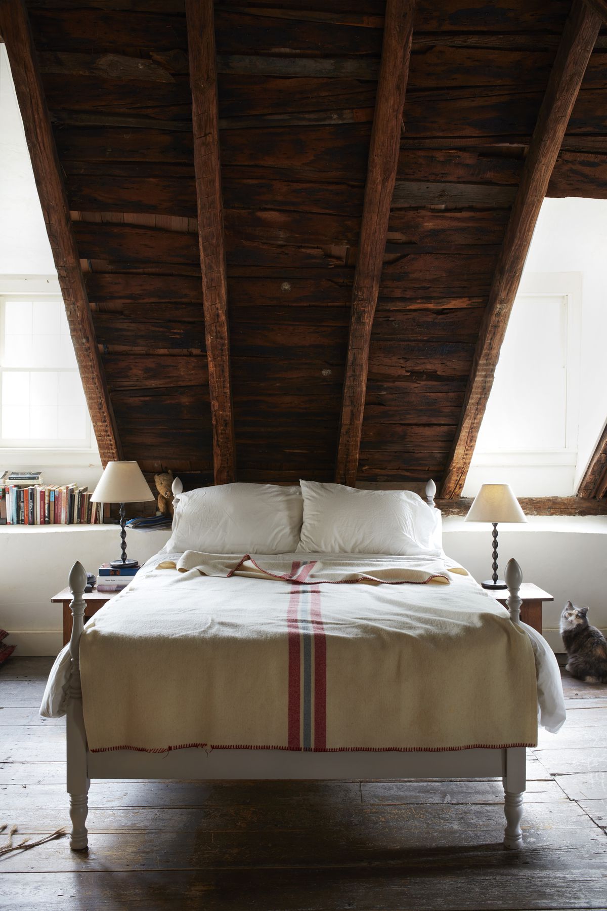 A low bed is tucked into an eave beneath a steeply pitched roof.