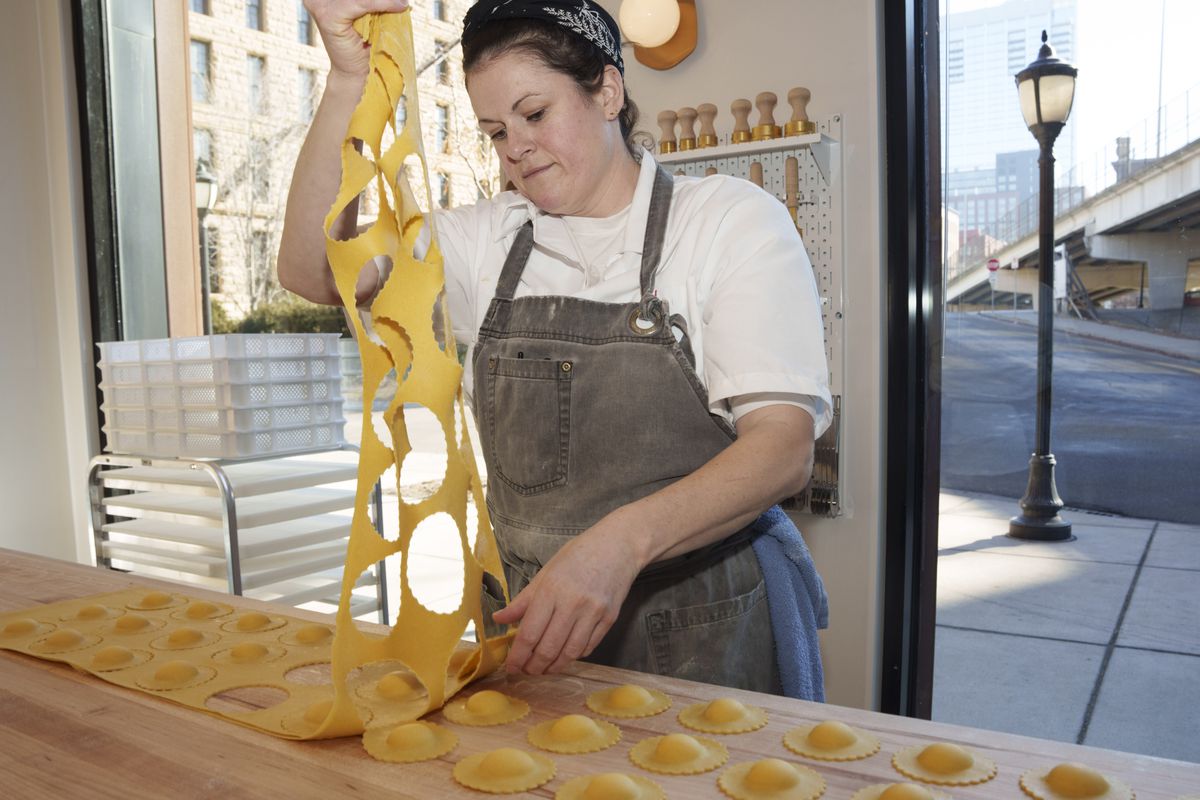 Rachel Cornelius McLeod pulls the excess pasta sheet dough up off the table, leaving the formed cappelletti behind.