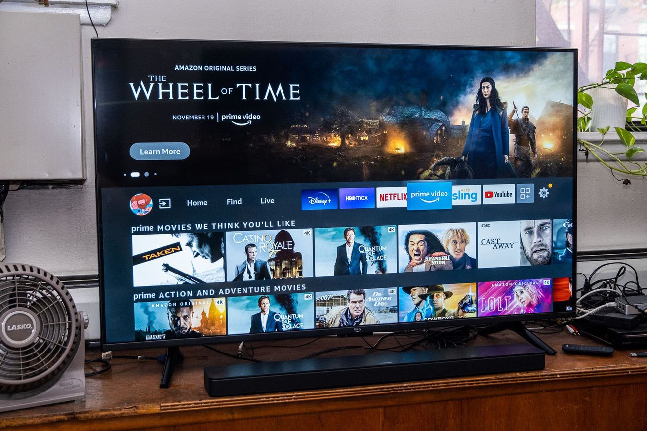 Amazon’s Fire TV Omni is turned on and sitting on a TV stand.