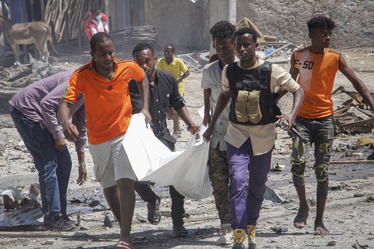 Rescuers carry away the body of a civilian who was killed in a blast in Mogadishu, Somalia, Wednesday, Jan. 12, 2022. A large explosion was reported outside the international airport in Somalia’s capital on Wednesday and an emergency responder said there were deaths and injuries. 