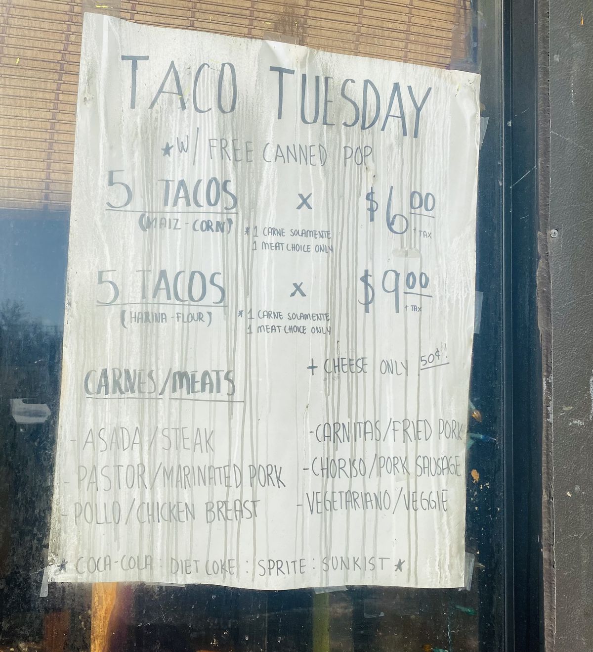 A sign with taco specials posted in the window of Taqueria El Rey.