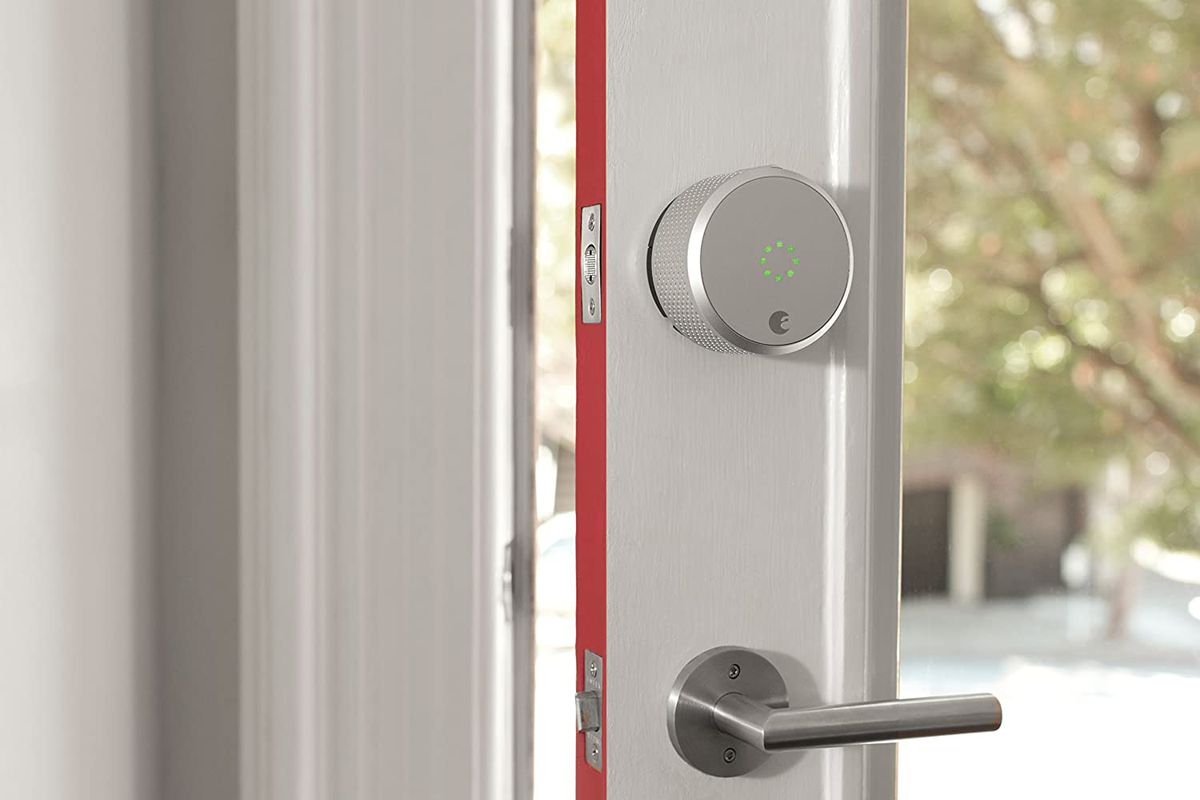 A close-up of a door lock and door knob on a door that is cracked open