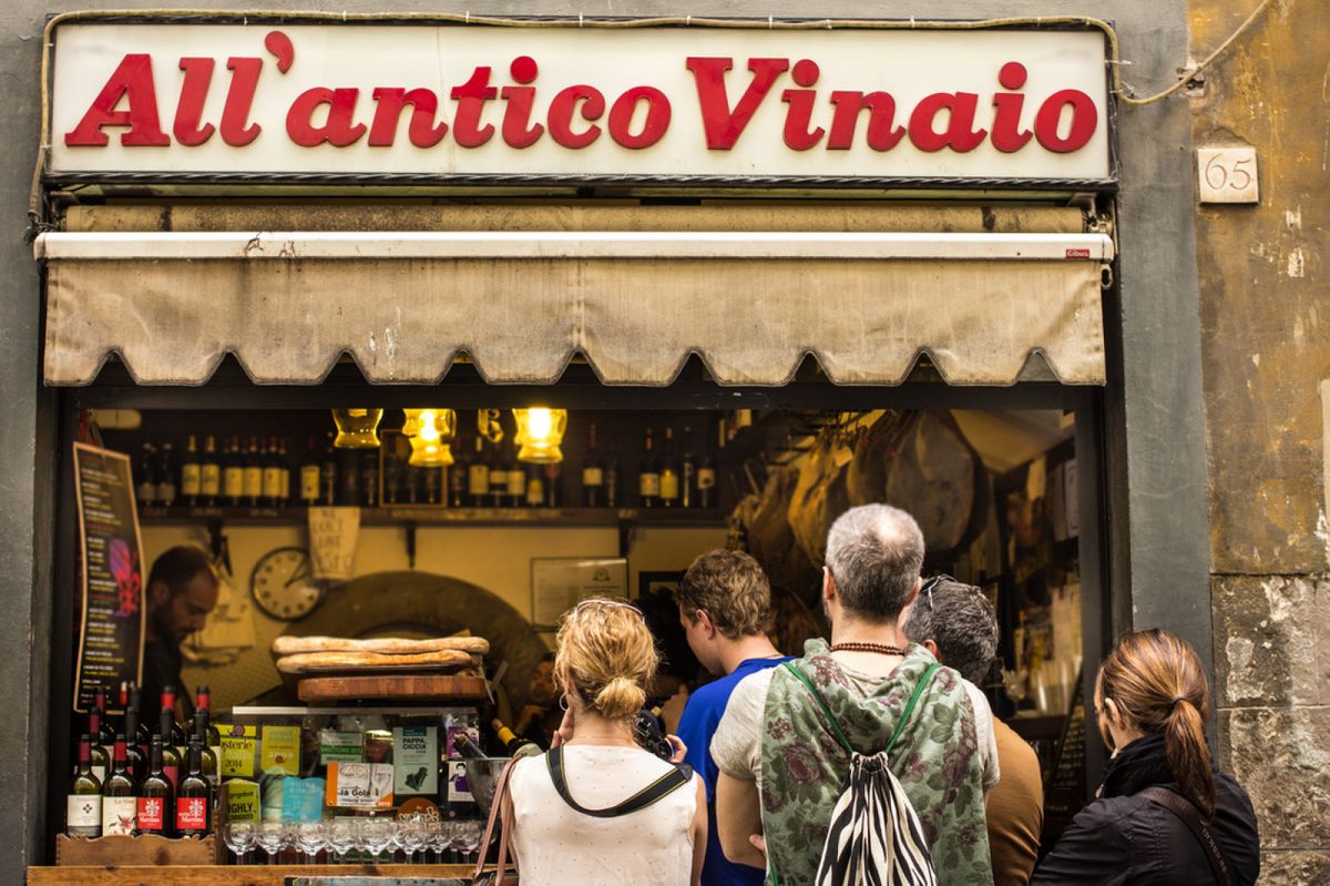All’Antico Vinaio storefront with customers waiting for hours for shaved meat sandwiches.