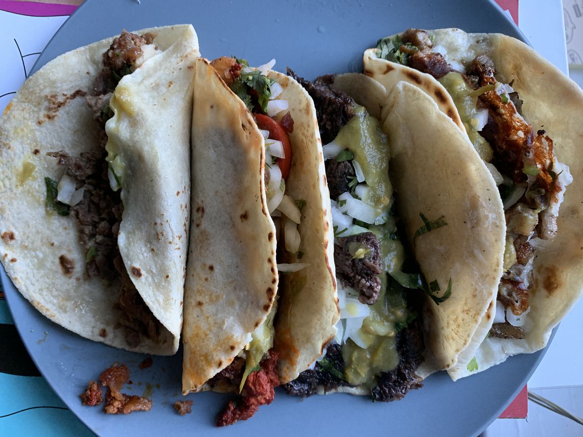 A blue-gray plate with four tacos.