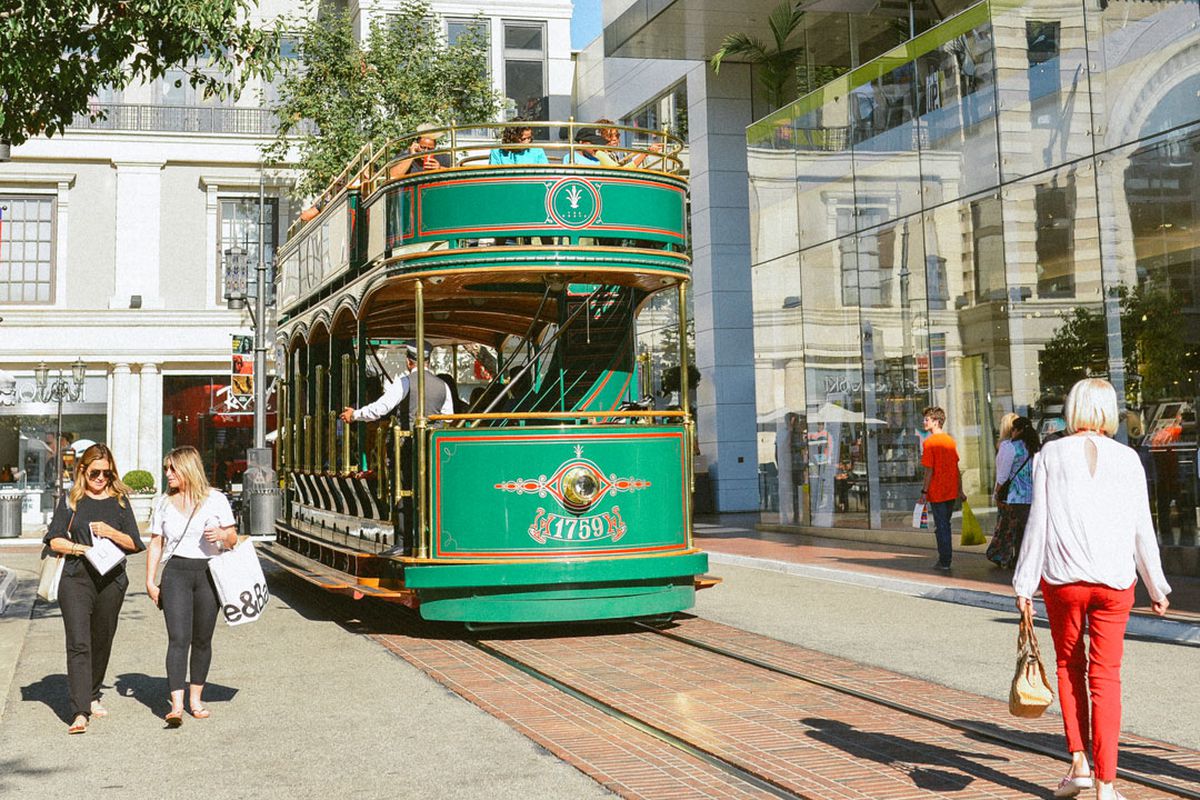 A light green trolley passed beyond customers at an upscale outdoor mall.