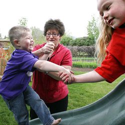 Jaxon Andersen, 3, gets some help from his grandmother, Brenda Thurston, and older sister, Kylee Andersen, 6, as he climbs up the slide in the backyard of their home in Hyrum on Saturday. Kylee's and Jaxon's parents were killed in a car accident a year and a half ago, along with Kylee's friend Hannah Roach.