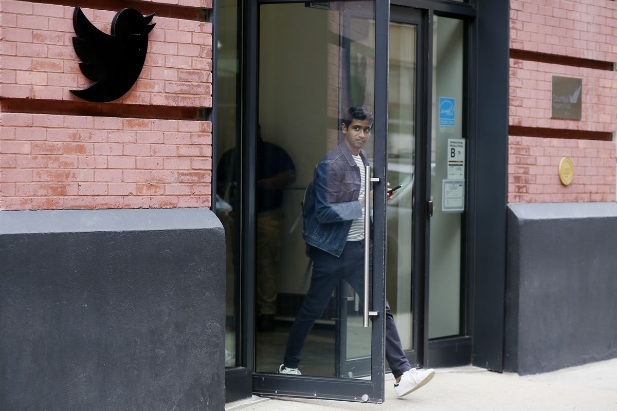 A person walking out of the door of an office building onto the sidewalk.