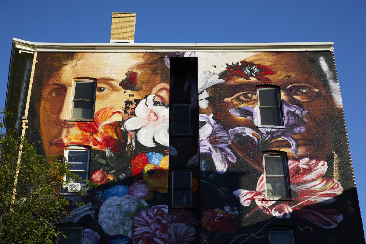 The exterior of a building with a colorful mural depicting two people, a man and a woman.
