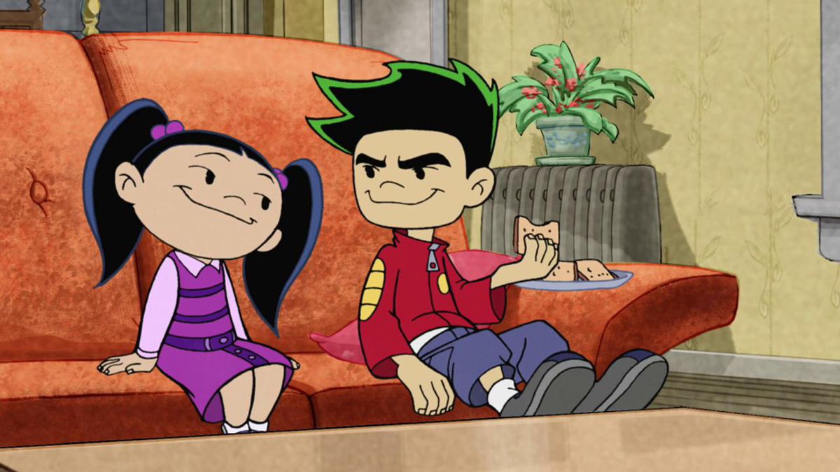 Two cartoon children on a couch, one of them eating cookies off a plate.