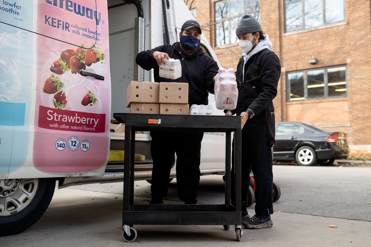 Juvenal Reyes (left) delivers boxes of kefir to Jorge Saldarriaga (right), founder of Grocery Run Club, at the group’s West Town storage facility on Friday, Nov. 13, 2020.