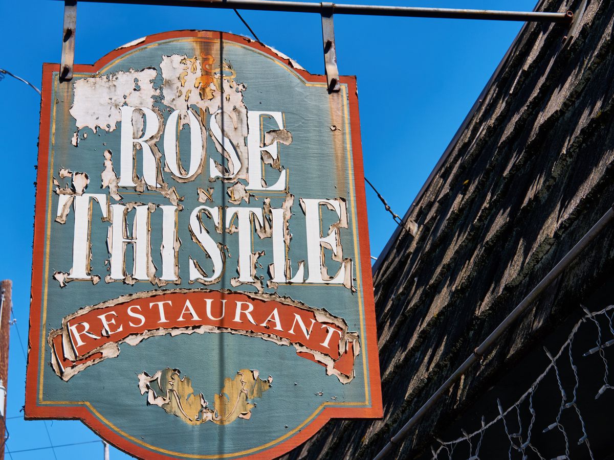 The weathered street sign for the Rose &amp; Thistle Restaurant.