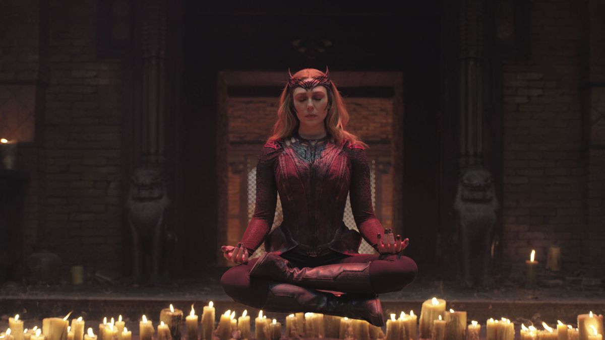 Elizabeth Olsen as Wanda Maximoff floats in the air in lotus position, eyes closed, above a circle of candles in Doctor Strange in the Multiverse of Madness.